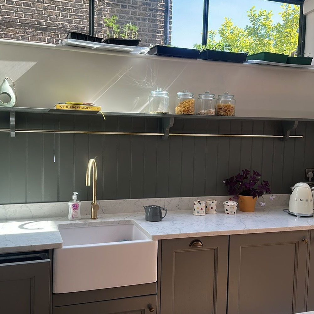 Kitchen with a brick splashback, ceramic sink and green tiling