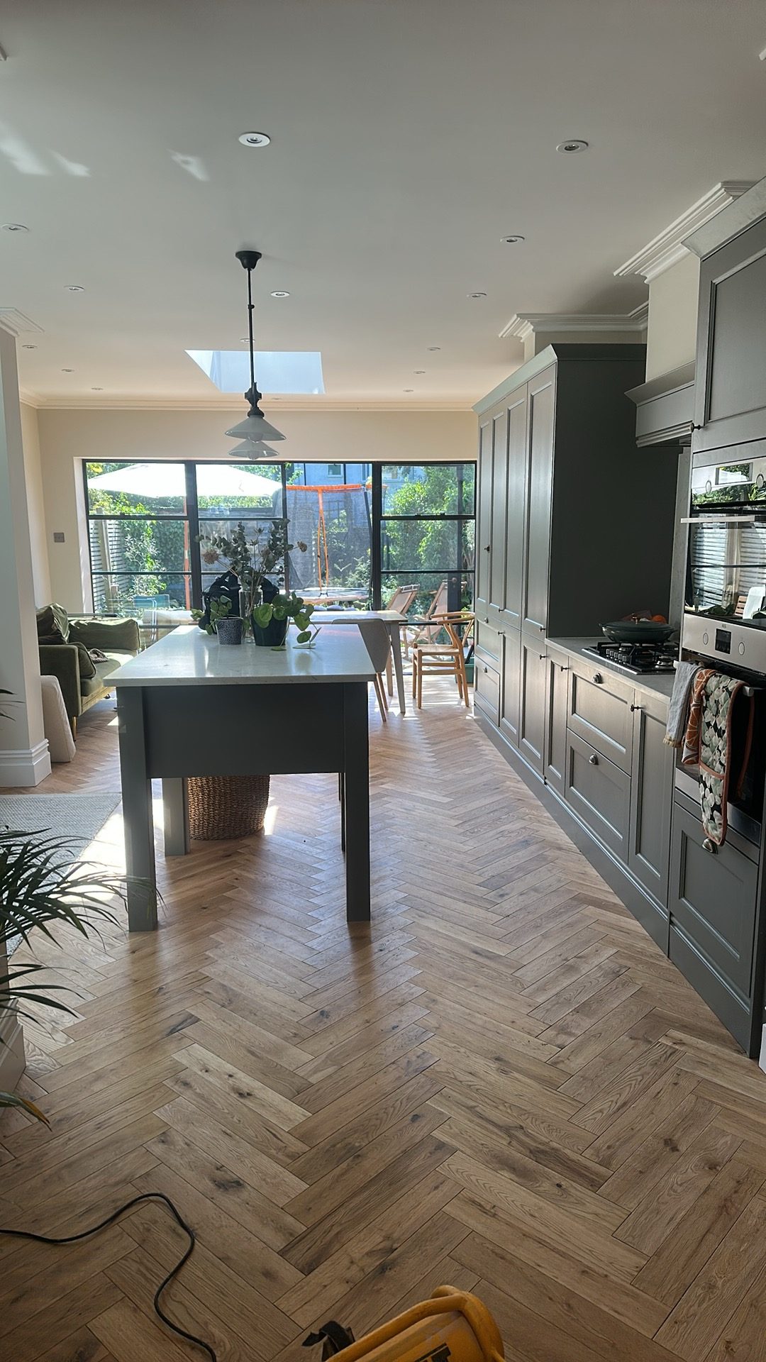 Open-plan kitchen and dining area with herringbone wood flooring