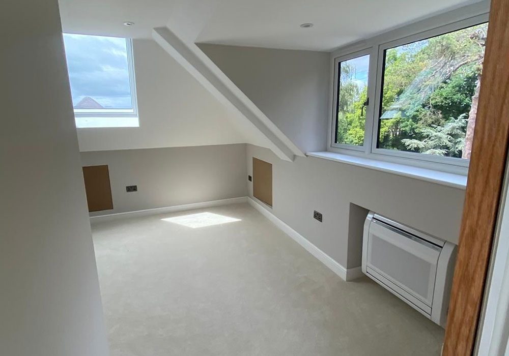 Completed loft conversion with a Velux roof window, radiator and finished walls
