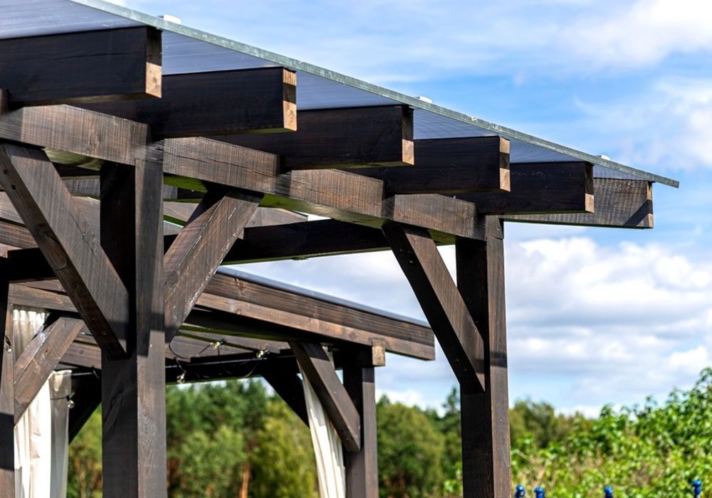 Timber-framed canopy with a glazed roof over an outdoor seating area